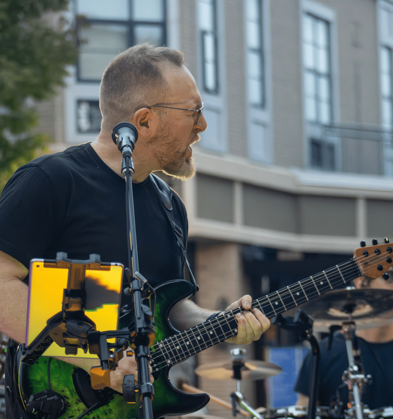 Musician playing electric guitar outdoors.
