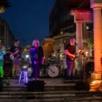 Band performing at an outdoor concert at night.
