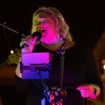 Woman performing at an outdoor concert at night.