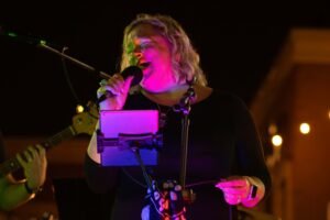 Woman performing at an outdoor concert at night.