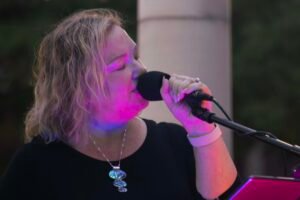 Woman performing at an outdoor concert at night.