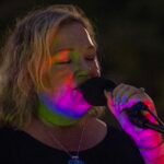 Woman performing at an outdoor concert at night.