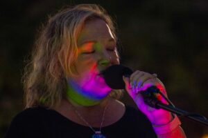 Woman performing at an outdoor concert at night.